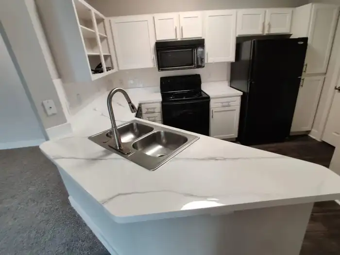 Kitchen countertops resurfaced in a white marble finish with white cabinets and dark plank flooring